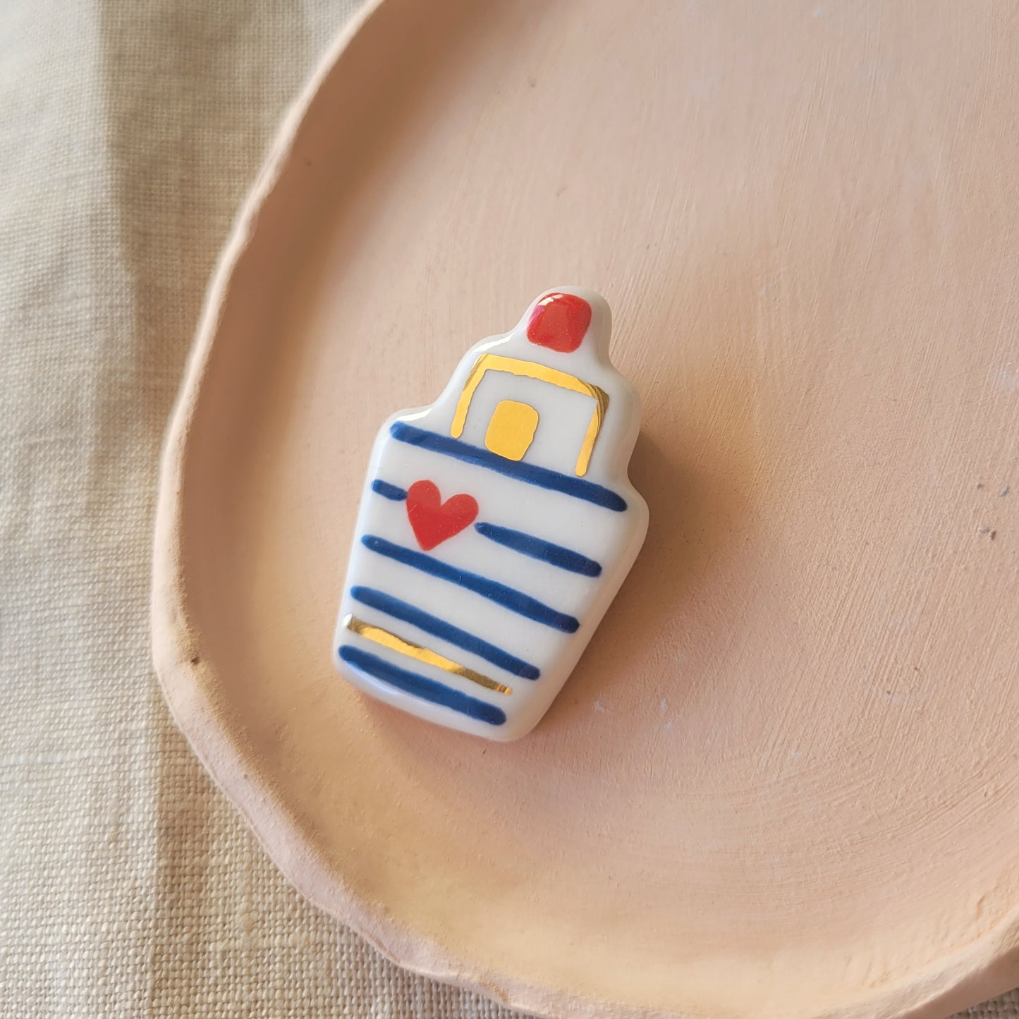 Porcelain brooch with gold "Boat with dark blue stripes"